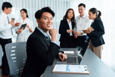 Portrait of focus young successful confident male manager, executive wearing business wear in harmony office arm crossed with blurred meeting background of colleagues, office worker.