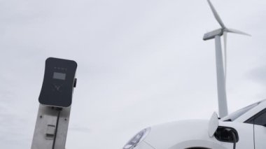 Çevreyi korumak için rüzgar türbininden yeşil ve yenilenebilir enerjiyle çalışan şarj istasyonunda şarj edilen gelişmiş gelecek enerji altyapısı konsepti.