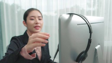 Masasında dizüstü bilgisayarla çalışan kulaklık ve mikrofon takan Asyalı müşteri destek operatörü. Hevesli kadın çalışanlar müşteri hizmetleri sunuyor, destekleyici çağrı merkezi temsilcisi müşterilere yardım ediyor.