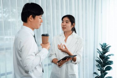 Manager advising guiding younger colleague with tablet in workplace. Couple businesspeople in formal wear working together on financial strategy as concept of teamwork and harmony in office.