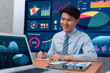 Portrait of successful confident businessman, manager or executive in business wear analyzing financial report with dashboard data on TV screen in the background at harmony office meeting room.