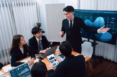 Confidence and asian businessman give presentation on financial analyzed by business intelligence in dashboard report to other people in board room meeting to promote harmony in workplace.