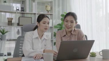 Ofis çalışma alanında birlikte çalışan iki genç hevesli iş kadını. Genç meslektaşlar tartışırken ve dizüstü bilgisayar kullanırken. Modern ofis çalışanları masada birlikte oturuyorlar..