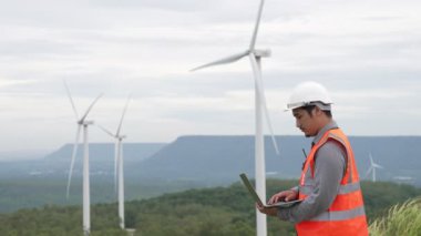 Kırsal kesimdeki bir tepenin tepesinde ya da dağda rüzgar çiftliğinde çalışan bir mühendis. Yenilenebilir ve sürdürülebilir enerjinin gelecekteki üretimi için yenilikçi bir ideal. Rüzgar türbininden enerji üretimi.