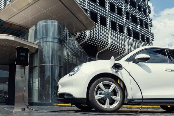 Progressive electric vehicle recharging battery at charging station powered by sustainable clean energy at city residential area. Eco-friendly vehicle concept.