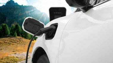 Elektro jeneratör sürücüsüyle enerji sürdürülebilir araba gücü, şarj istasyonunda şarj edilen batarya, ilerici seyahat konsepti için dağ zeminine sahip. Temiz ortamın sembolü olarak doğadaki EV otomobil.