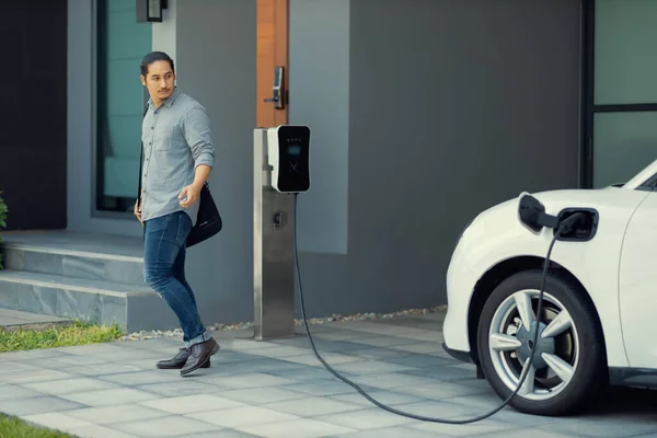 Progressive Asian Man Electric Car Home Charging Station Concept Use — стоковое фото