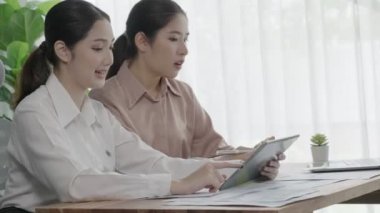 Ofis çalışma alanında birlikte çalışan iki genç hevesli iş kadını. Genç meslektaşlar tartışırken ve dizüstü bilgisayar kullanırken. Modern ofis çalışanları masada birlikte oturuyorlar..