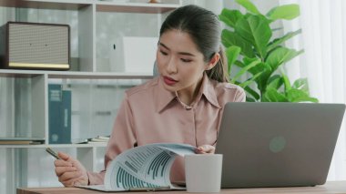 Ofiste çalışan ve dizüstü bilgisayar yazan hevesli bir iş kadını. Masasında oturmuş laptopla çalışan güzel bir ofis hanımı..