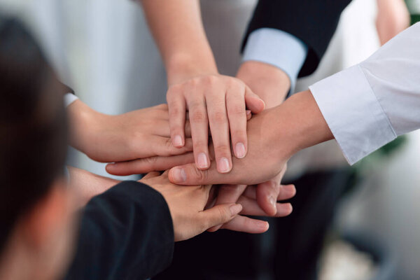 Top view closeup business team of suit-clad businesspeople join hand stack together. Colleague collaborate and work together to promote harmony and teamwork concept in office workplace.