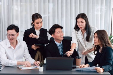 Harmony in office concept as business people analyzing dashboard paper together in workplace. Young colleagues give ideas at manager desk for discussion or strategy planning about project.