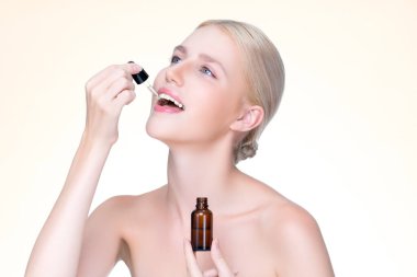 Closeup personable portrait of beautiful woman applying essential oil bottle for skincare product. Cannabis extracted CBD oil dropper for treatment and cannabinoids concept in isolated background.