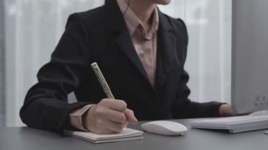 Masasında dizüstü bilgisayarla çalışan kulaklık ve mikrofon takan Asyalı müşteri destek operatörü. Hevesli kadın çalışanlar müşteri hizmetleri sunuyor, destekleyici çağrı merkezi temsilcisi müşterilere yardım ediyor.