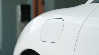 İlerici adam evindeki elektrikli aracın aküsüne emisyonsuz güç bağlantısı kuruyor. Elektrikli araç elektrik istasyonundan EV araba aküsüne kabloyla şarj oluyor.