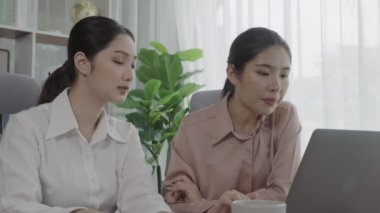 Ofis çalışma alanında birlikte çalışan iki genç hevesli iş kadını. Genç meslektaşlar tartışırken ve dizüstü bilgisayar kullanırken. Modern ofis çalışanları masada birlikte oturuyorlar..