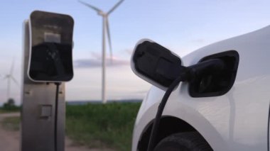 Çevreyi korumak için rüzgar türbininden yeşil ve yenilenebilir enerjiyle çalışan şarj istasyonunda şarj edilen gelişmiş gelecek enerji altyapısı konsepti.