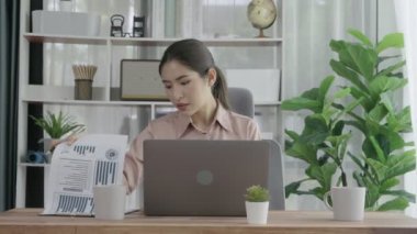 Ofiste çalışan ve dizüstü bilgisayar yazan hevesli bir iş kadını. Masasında oturmuş laptopla çalışan güzel bir ofis hanımı..