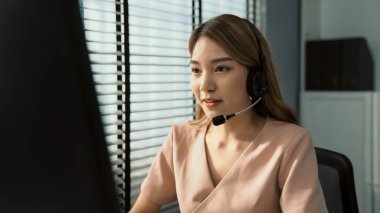 Competent female operator working on computer and while talking with clients. Concept relevant to both call centers and customer service offices.