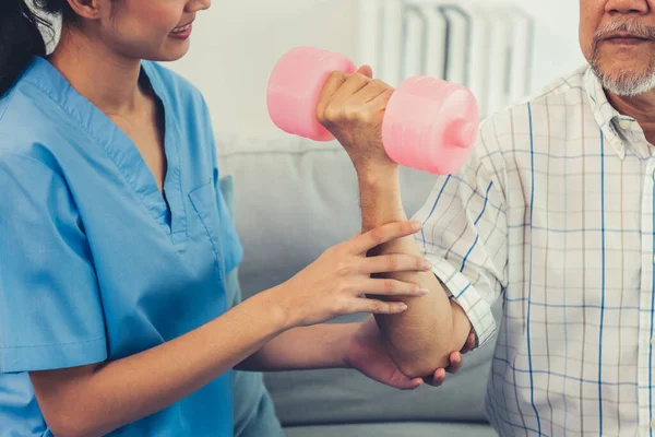 stock image Contented senior patient doing physical therapy with the help of his caregiver. Senior physical therapy, physiotherapy treatment, nursing home for the elderly