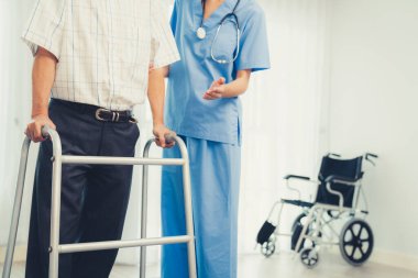 Physiotherapist assists her contented senior patient on folding walker. Recuperation for elderly, seniors care, nursing home.