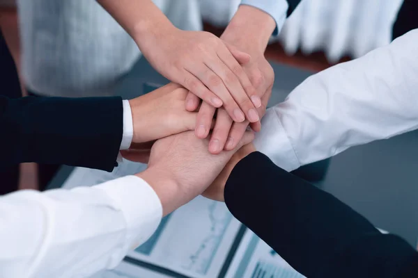 Top view closeup business team of suit-clad businesspeople join hand stack together. Colleague collaborate and work together to promote harmony and teamwork concept in office workplace.