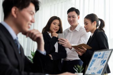 Harmony in office concept as business people analyzing dashboard paper together in workplace. Young colleagues give ideas at manager desk for discussion or strategy planning about project.