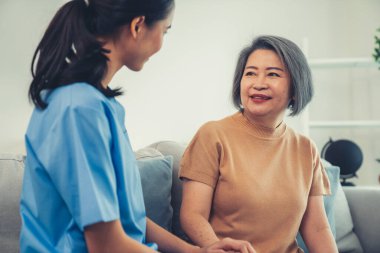 A contented senior woman visited by her personal caregiver and hold each others hands.
