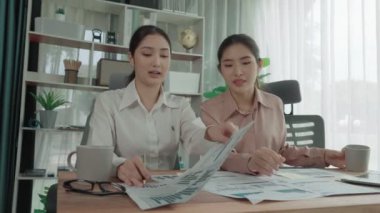 Ofis çalışma alanında birlikte çalışan iki genç hevesli iş kadını. Genç meslektaşlar tartışırken ve dizüstü bilgisayar kullanırken. Modern ofis çalışanları masada birlikte oturuyorlar..