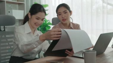Ofis çalışma alanında birlikte çalışan iki genç hevesli iş kadını. Genç meslektaşlar tartışırken ve dizüstü bilgisayar kullanırken. Modern ofis çalışanları masada birlikte oturuyorlar..