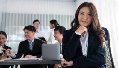 Focus portrait of female manger, businesswoman in the harmony meeting room with blurred of colleagues working together, analyzing financial paper report and dashboard data in background.