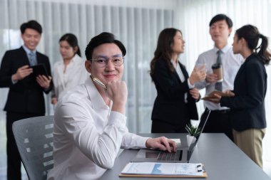 Portrait of focus young successful confident male manager, executive wearing business wear in harmony office arm crossed with blurred meeting background of colleagues, office worker.