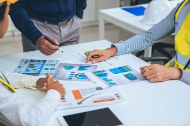 Engineers and competent employer discussing plans and blueprints together with tablet in the office. Concept of team contribution of ideas for engineering project.