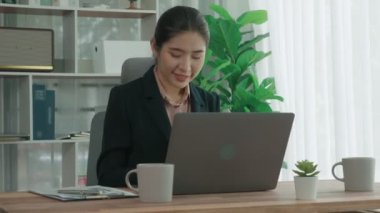 Ofiste çalışan ve dizüstü bilgisayar yazan hevesli bir iş kadını. Masasında oturmuş laptopla çalışan güzel bir ofis hanımı..