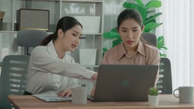 Ofis çalışma alanında birlikte çalışan iki genç hevesli iş kadını. Genç meslektaşlar tartışırken ve dizüstü bilgisayar kullanırken. Modern ofis çalışanları masada birlikte oturuyorlar..