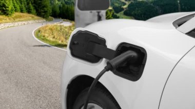 Tepe yolundaki şarj istasyonunda elektrikli arabanın çevresel farkındalığı için yenilikçi bir kavram. EV araba temiz çevre için yenilenebilir enerjiden güç alıyor.