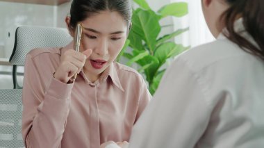 Ofis çalışma alanında birlikte çalışan iki genç hevesli iş kadını. Genç meslektaşlar tartışırken ve dizüstü bilgisayar kullanırken. Modern ofis çalışanları masada birlikte oturuyorlar..