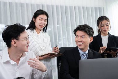 Harmony in office concept as business people analyzing dashboard paper together in workplace. Young colleagues give ideas at manager desk for discussion or strategy planning about project.