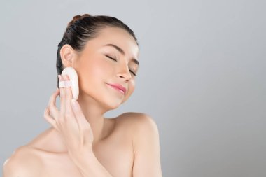 Glamorous beautiful female model applying cushion powder for facial makeup concept. Portrait of flawless perfect cosmetic skin woman put powder puff on her face in isolated background.