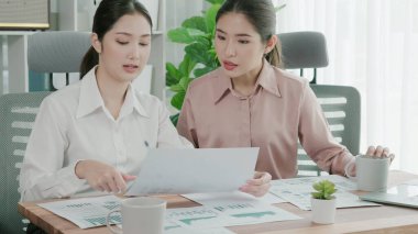 Ofis çalışma alanında birlikte çalışan iki genç hevesli iş kadını. Genç meslektaşlar tartışırken ve dizüstü bilgisayar kullanırken. Modern ofis çalışanları masada birlikte oturuyorlar..