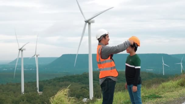 田舎の丘や山の上の風力発電所で彼の息子とエンジニア 再生可能エネルギー 持続可能なエネルギーの将来の生産のための進歩的な理想 風力タービンからの発電 — ストック動画