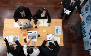 Top view manager or office worker give presentation in harmony conference room to business colleague, BI data dashboard on screen and pile of financial analyzed data reports on meeting table.