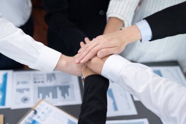 Top view closeup business team of suit-clad businesspeople join hand stack together. Colleague collaborate and work together to promote harmony and teamwork concept in office workplace.