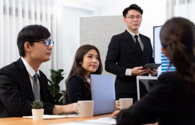 Confidence and asian businessman give presentation on financial analyzed by business intelligence in dashboard report to other people in board room meeting to promote harmony in workplace.