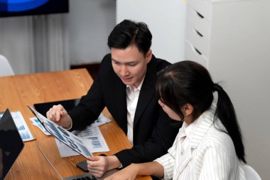 Harmony in office concept as business people analyzing dashboard paper together in workplace. Young colleagues give ideas at manager desk for discussion or strategy planning about project.