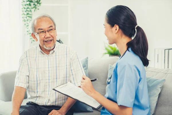 Young Female Doctor Inquires Personal Information Contented Senior Home Medical — Foto de Stock