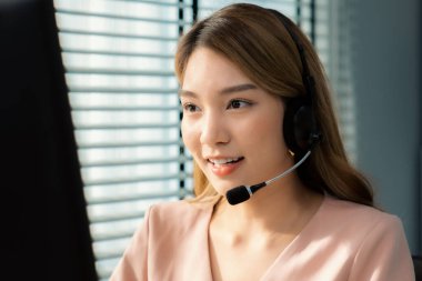 Competent female operator working on computer and while talking with clients. Concept relevant to both call centers and customer service offices.