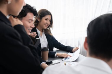 Harmony in office concept as business people analyzing dashboard paper together in workplace. Young colleagues give ideas at manager desk for discussion or strategy planning about project.