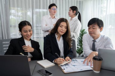 Harmony in office concept as business people analyzing dashboard paper together in workplace. Young colleagues give ideas at manager desk for discussion or strategy planning about project.