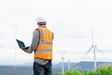 Kırsal kesimdeki bir tepenin tepesinde ya da dağda rüzgar çiftliğinde çalışan bir mühendis. Yenilenebilir ve sürdürülebilir enerjinin gelecekteki üretimi için yenilikçi bir ideal. Rüzgar türbininden enerji üretimi.