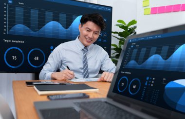 Portrait of successful confident businessman, manager or executive in business wear analyzing financial report with dashboard data on TV screen in the background at harmony office meeting room.